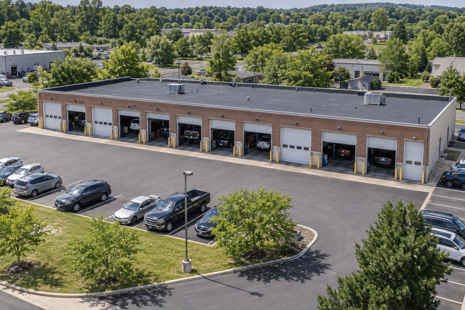 Illustrative aerial view of a large service center with multiple bays and parked vehicles in a Philadelphia-area suburban setting